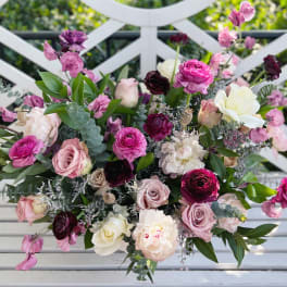 Mixed bouquet of pink, white, and burgundy flowers on a white bench