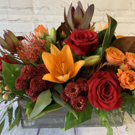 Mixed bouquet with red and orange roses, lilies, and dark mums