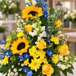 Yellow and blue mixed flower arrangement with sunflowers and roses