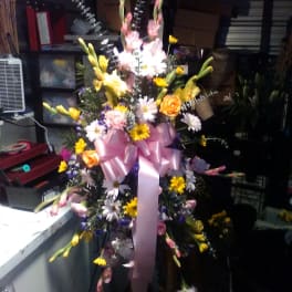 Tall mixed flower spray with a pink ribbon bow