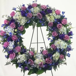 Purple and blue floral wreath on a black stand