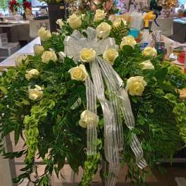 Large white rose arrangement with a silver ribbon and cascading greenery