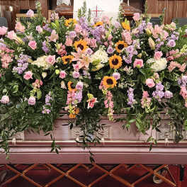 Large casket spray with pink and lavender flowers and sunflowers