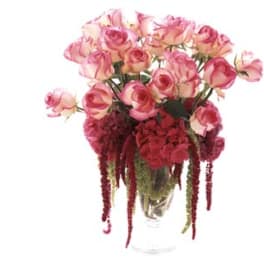 Pink roses and red hanging flowers in a clear vase