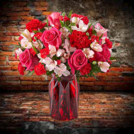 Pink and red bouquet in a red glass vase