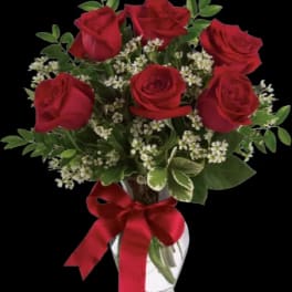 Red roses in a clear glass vase with a red ribbon