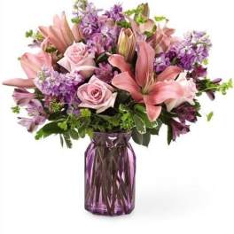 Pink lilies and roses with purple flowers in a purple vase