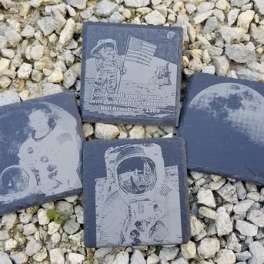 Four square slate tiles with astronaut and moon designs on gravel