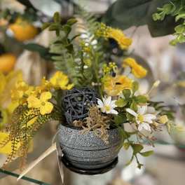 Small floral arrangement with yellow and white flowers in a gray pot