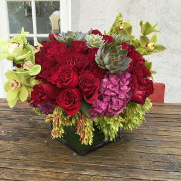 Red roses with green orchids and succulents in a black vase