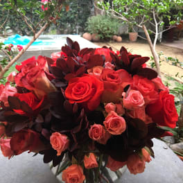 Red and pink roses arranged in a clear glass vase