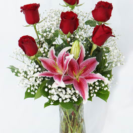 Red roses and pink lilies in a clear glass vase