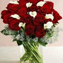 Red roses and white calla lilies in a clear glass vase