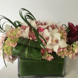 Pink and white floral arrangement in a square glass vase