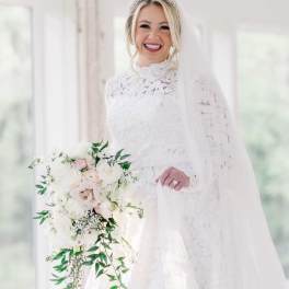 Bride in a white lace gown holding a cascading bouquet of white and blush flowers