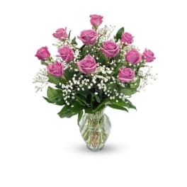 Pink roses arranged in a clear glass vase with white filler flowers
