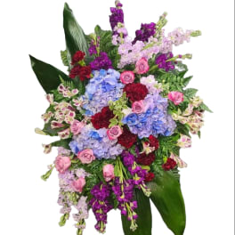 Large standing floral spray with hydrangeas, roses, and purple stock