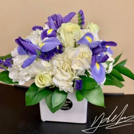 Bouquet of white roses, hydrangeas, and purple irises in a white vase