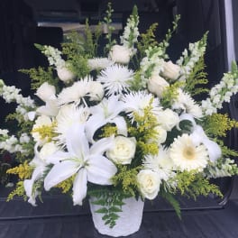 White floral arrangement in a textured white vase with lilies and roses