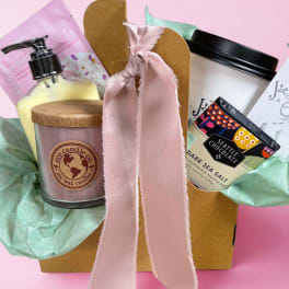 Gift basket with a candle, lotion, and chocolate bar tied with a pink ribbon