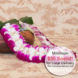 Purple and white orchid lei draped beside a wooden bowl on a patterned surface