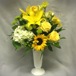 Yellow lilies and roses with a sunflower in a white vase