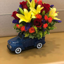 Bouquet of red roses and yellow lilies in a blue toy truck