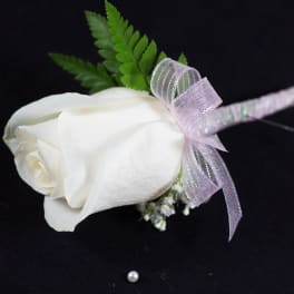 White rose boutonniere with a lavender ribbon and green fern