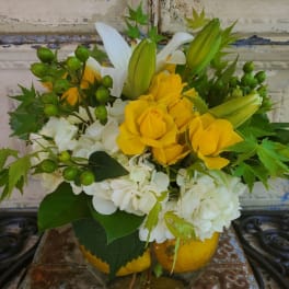 Yellow roses and white lilies in a glass vase with white hydrangeas