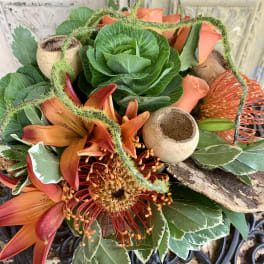 Orange lilies and a red-orange pincushion protea in a decorative arrangement