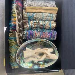 Box of bundled sage, feathers, and an abalone shell with ribbon