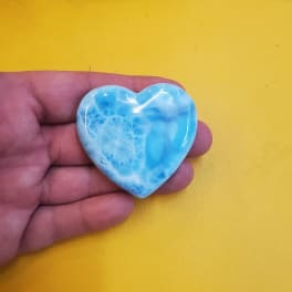 Hand holding a small blue heart-shaped stone