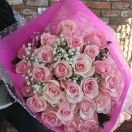 Bouquet of pale pink roses with baby's breath in bright pink wrap