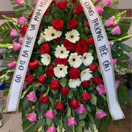 Large funeral wreath of red and pink roses with white daisies and ribbons