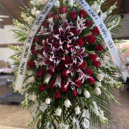 Large funeral wreath of red roses and white lilies with condolence ribbons