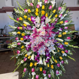 Large standing floral spray with pink, yellow, white, and purple blooms