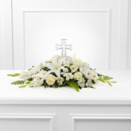 White floral casket spray with a clear cross centerpiece