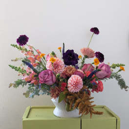 Mixed bouquet in a white vase with pink, purple, and peach flowers