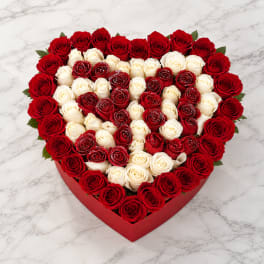 Heart-shaped box of red and white roses on a marble surface