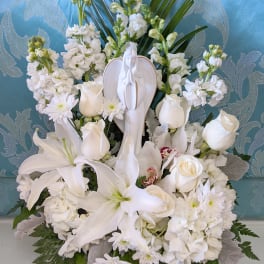 White floral sympathy arrangement with a praying angel figurine