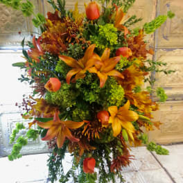 Tall autumn floral arrangement with orange lilies and green blooms