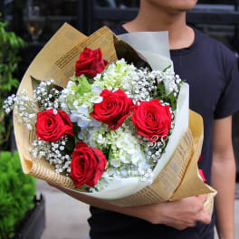 Bouquet of red roses and white hydrangeas wrapped in paper