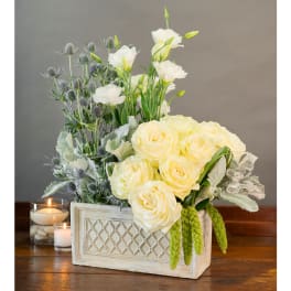 Cream roses and white blooms in a rectangular planter with candles nearby