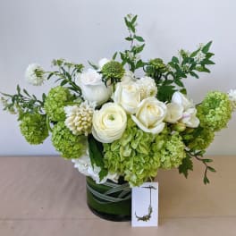 White and green floral arrangement in a dark glass vase
