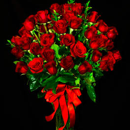 Bouquet of red roses in a clear glass vase with a red ribbon