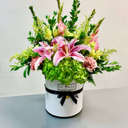 Pink lilies and green hydrangeas in a white hatbox