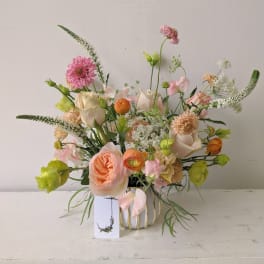 Mixed bouquet of pink, peach, white, and green flowers in a vase