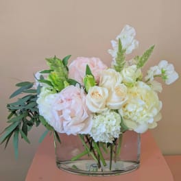Pastel bouquet of roses, hydrangea, and white blooms in a clear glass vase