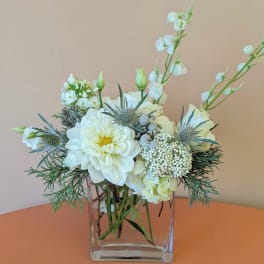 White floral arrangement in a clear square vase