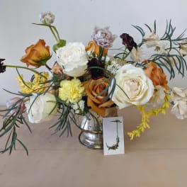 Mixed bouquet of roses, peonies, and carnations in a silver vase